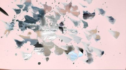 Abstract splatter of gray, silver and beige paint shapes scattered across a pale pink background