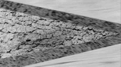 A blurred diagonal close up of layered rock and gravel, motion streaked in black and white