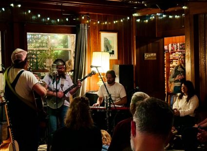 Band performing live music indoors under strings of warm lights
