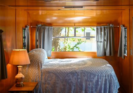 Vintage trailer bedroom with wood paneling and a blue patterned bedspread